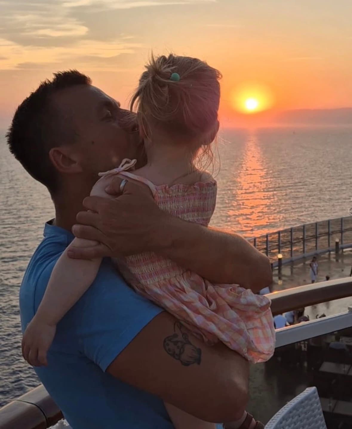 A father holding his daughter at sunset by the sea
